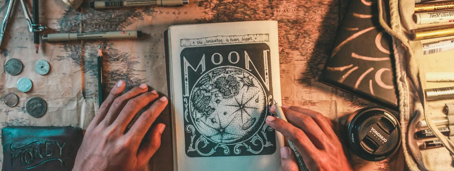 Livre Moon, stylo et carte du monde représentant l'étude de la destinée par nos praticiens